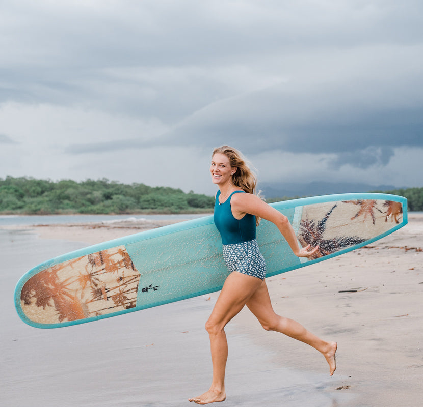 Photographer Kristen M. Brown of Samba to the Sea running on the beach with her surfboard to go surf in Tamarindo, Costa Rica.