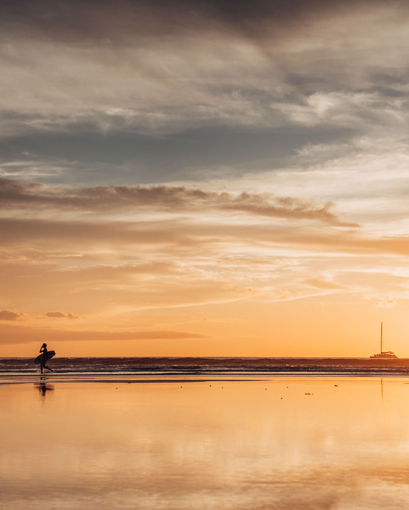 Surfers walking on the beach during a gorgeous sunset in Costa Rica. Photographed by Kristen M. Brown, Samba to the Sea for The Sunset Shop.