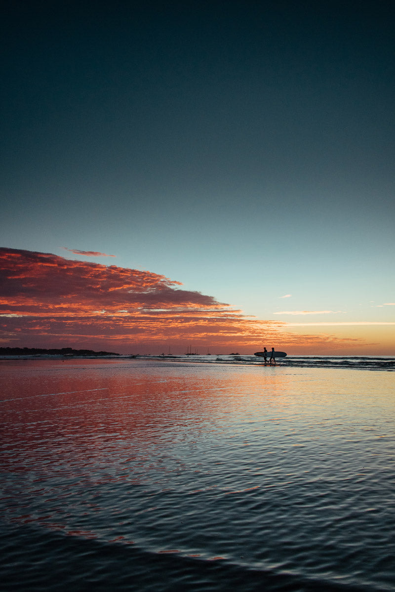 Surfers walking on the beach during sunset in Costa Rica. Fine art beach photography print Photographed by Kristen M. Brown, Samba to the Sea for The Sunset Shop.