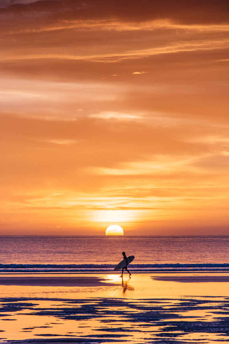 Surfer walking on the beach during a pretty sunset in Tamarindo Costa Rica. Photographed by Kristen M. Brown, Samba to the Sea for The Sunset Shop.