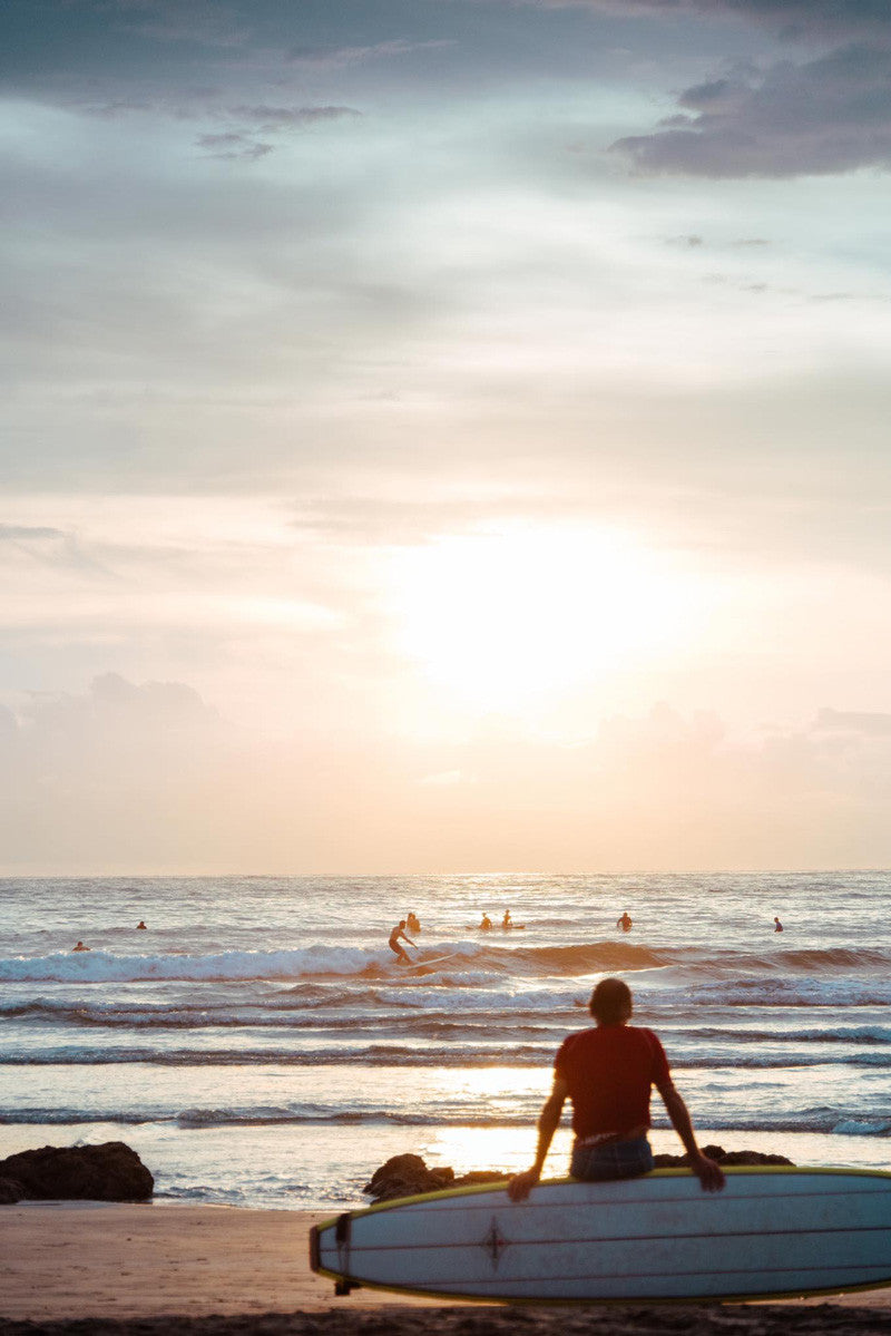 Surfer watching sunset from the beach in Tamarindo Costa Rica. Photographed by Kristen M. Brown, Samba to the Sea x The Sunset Shop.