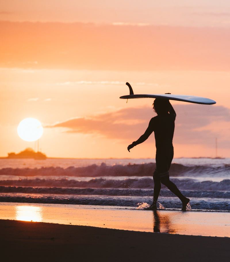 Surfer walking on the beach during sunset in Costa Rica. Fine art beach photography print Photographed by Kristen M. Brown, Samba to the Sea for The Sunset Shop.