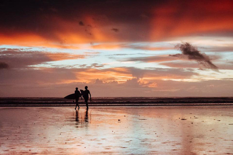 Surfers walking on the beach during sunset over the Pacific Ocean in Tamarindo Costa Rica. Photographed by Kristen M. Brown Samba to the Sea.