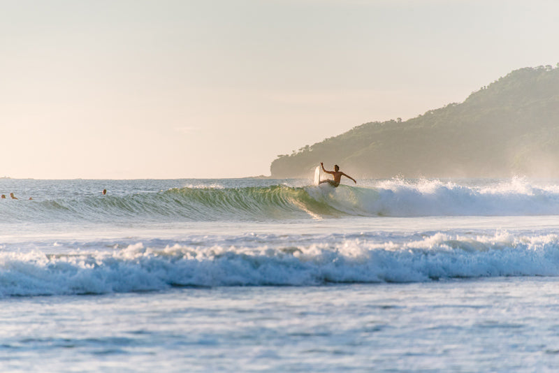 Surfer catching a wave in Tamarindo Costa Rica. Photographed by Kristen M. Brown, Samba to the Sea for The Sunset Shop.