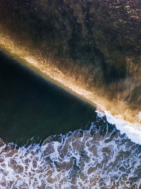 Aerial surfer print by Samba to the Sea at The Sunset Shop. Image is an aerial photo of surfer dropping in on a wave in Tamarindo, Costa Rica.