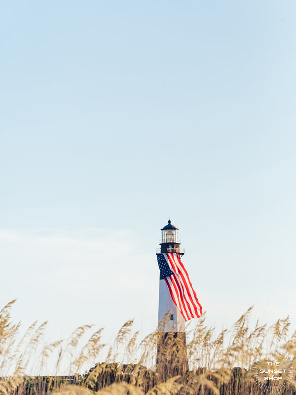 There she was, dancing in the sea breeze with the sea grass and shimmering in the late afternoon sun! Majestic American flag hanging from the Tybee Island Lighthouse in Tybee Island, GA. Photographed by Kristen M. Brown, Samba to the Sea for The Sunset Shop.