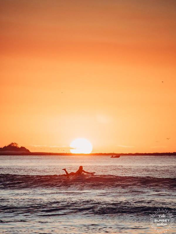 Female surfer paddling out during sunset in Tamarindo, Costa Rica. Photographed by Kristen M. Brown of Samba to the Sea for The Sunset Shop.