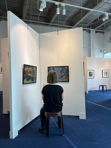 Lady seated looking at paintings in the first seated art exhibition in Singapore