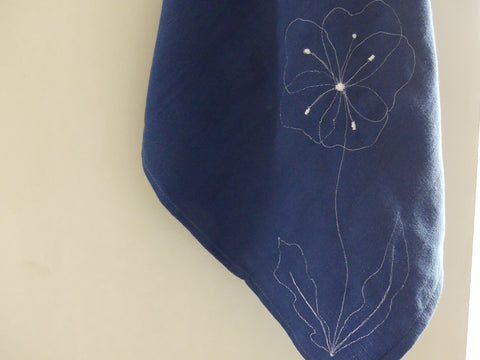 a blue tea towel with a white flower sewn to it