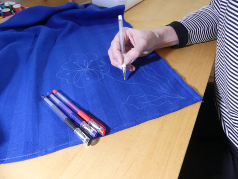 drawing a flower on a teatowel with a white heat erasable fabric marker