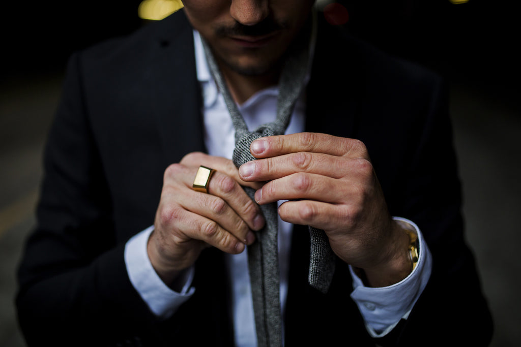 Man With Gold Signet Ring Tying A Tie