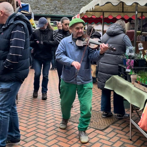 A fiddler walks around Stroud Farmers' Market