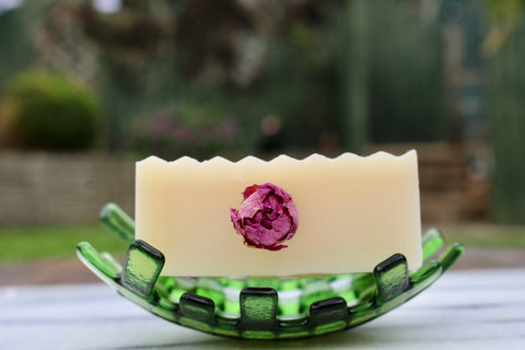 College Green soap with rose bud inserted in the centre, sat on a green glass soap dish