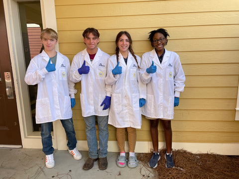 A group of highschool biology students in their lab coats. They are a part of a biotech course in grade 12. Ready to learn about genetic engineering through Amino Labs' science kits!