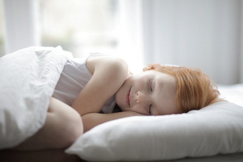 child with red hair sleeping peacefully on white pillow with white blanket