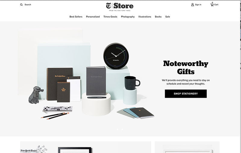 New york times store header with elegant stationery, a clock and a cta to shop for noteworthy gifts