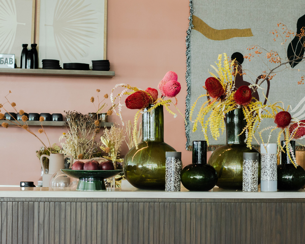 dark forest green glass handblown vases and retro vases from HKliving designed by Urban Nest at the counter of 21grams at Meyan Mall. The dripping bowl on base emerald green is filled with iconic red apples.