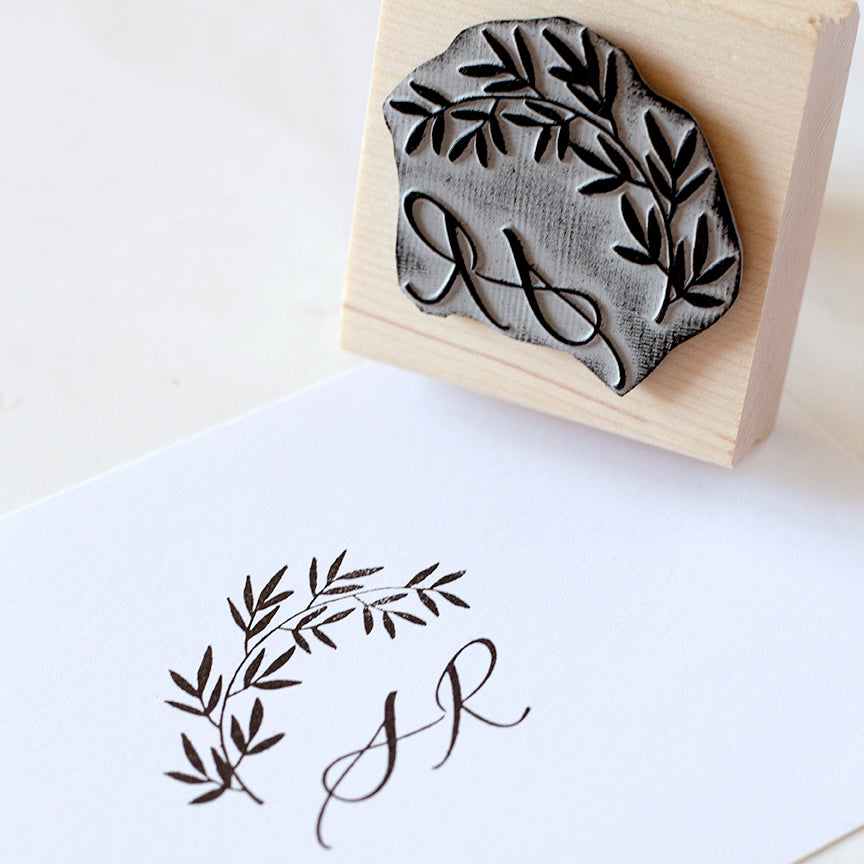 A Botanical Monogram Rubber Stamp Above A Black Stamped Impression on White Paper| How to Use a Rubber Stamp | Heirloom Seals