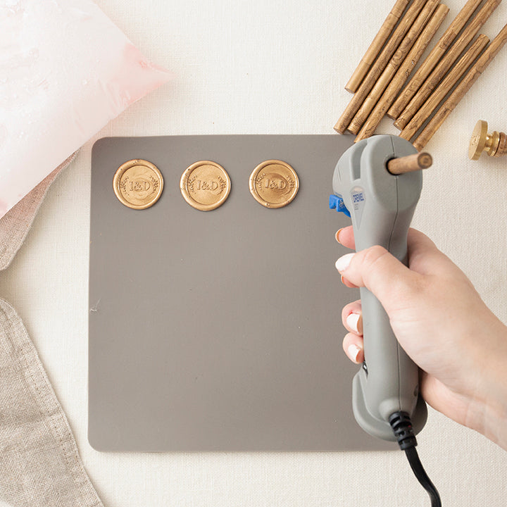 A Row of Wax Seals being Stamped onto a Silicone Mat with a Hot Glue Gun  | How to Make Wax Seals | Heirloom Seals