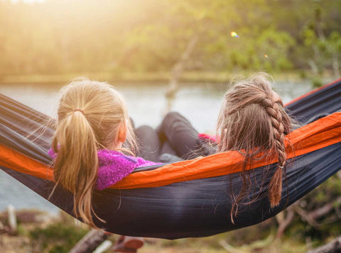 two girls sat in a hammock outdoors