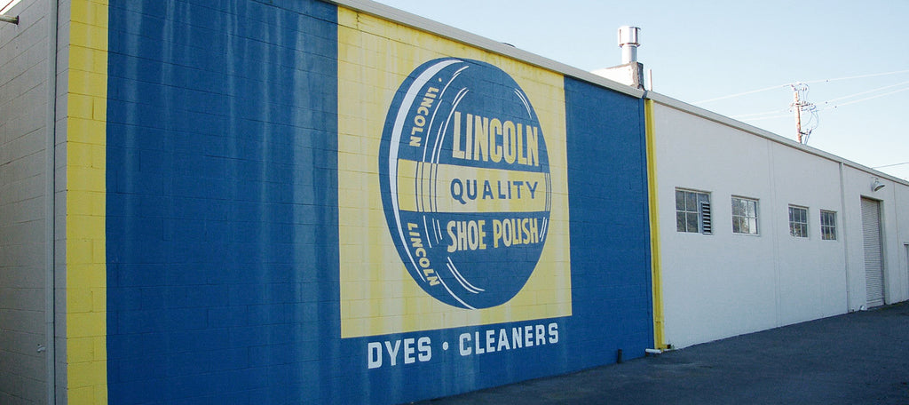 The wall of a business painted blue and yellow with a shoe polish can the reads "Lincoln Quality Shoe Polish"