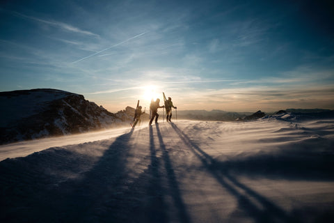 skiers on a slope with the sunset behind by Joris Berthelot on Unsplash.com