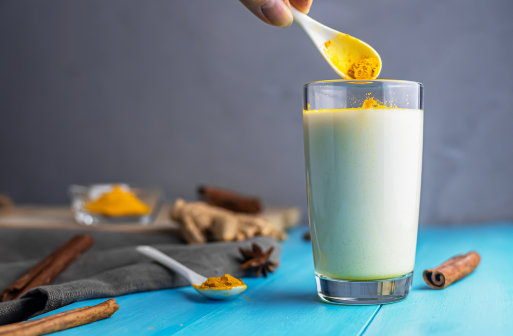 Turmeric powder getting put in a glass of milk