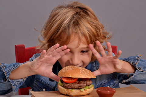 young boy about to eat a burger