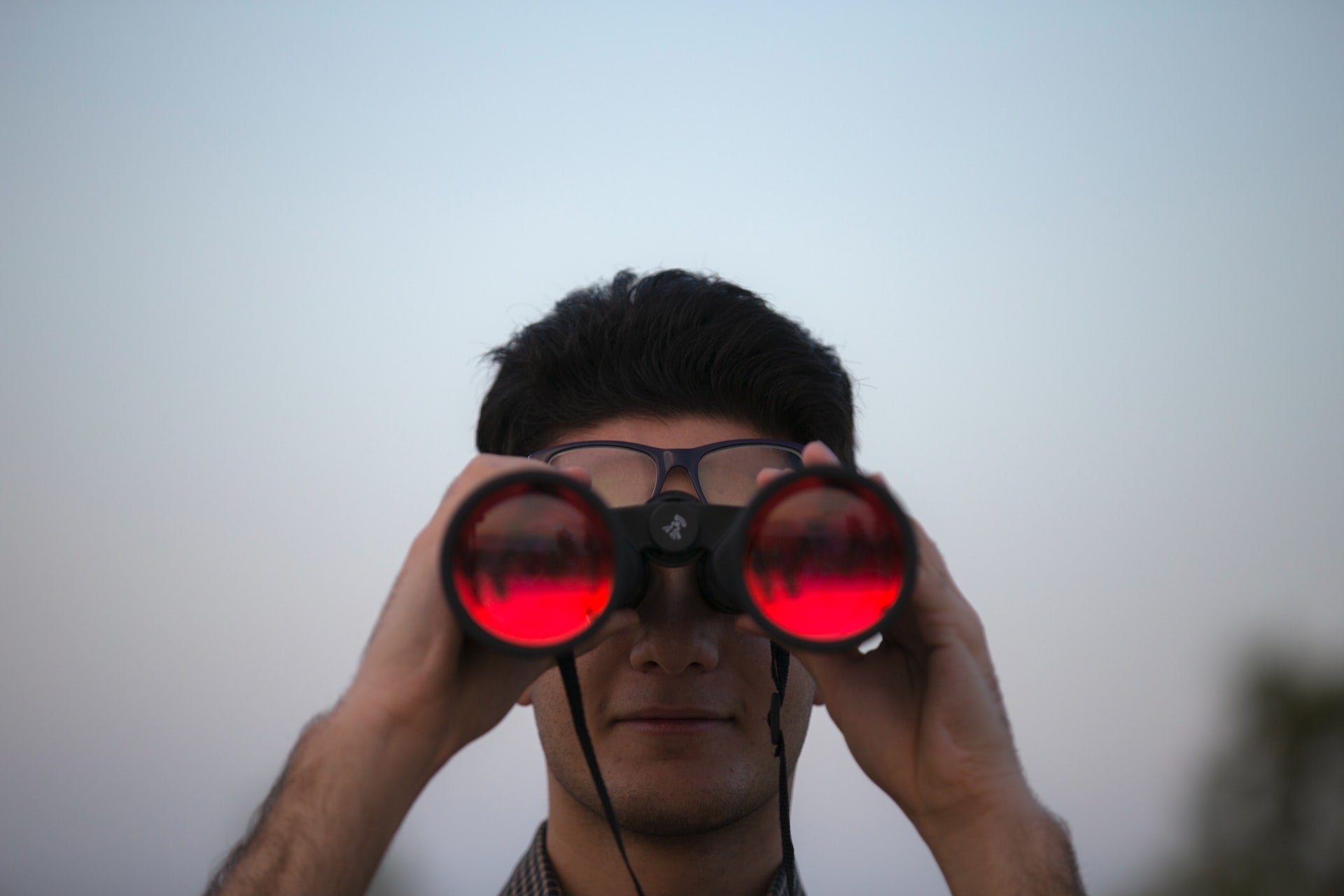 man looking into distance with binoculars