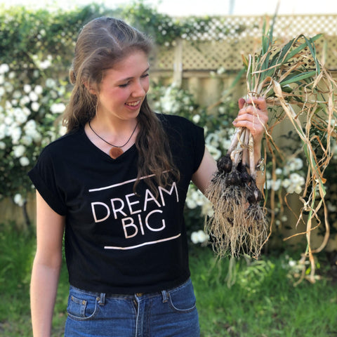 Dana holding her newly harvested garlic bulbs