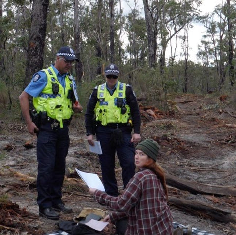 Activist being arrested by 2 police officers in forest