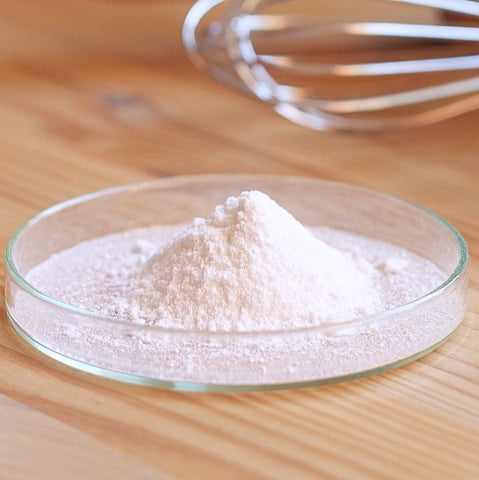 Small pile of bicarbonate of soda with cooking utensils in the background