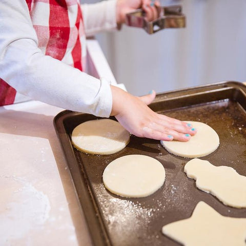 Child placing cookies for baking on a tray