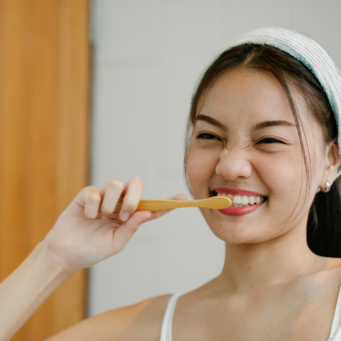 asian lady brushing her teeth and smiling