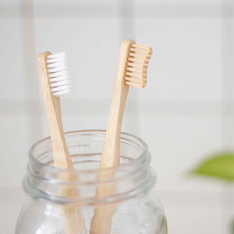 two wooden toothbrushes in a jar