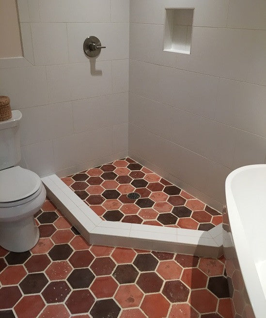 Blending hexagon tiles in different shades of red creates a spectacular contrast to the white walls and fixtures in this contemporary bath