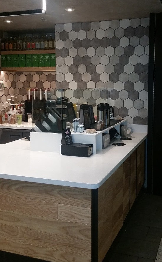 Glazed hexagon ceramic tiles in black, white and gray provide an eye-catching accent wall for this Starbucks
