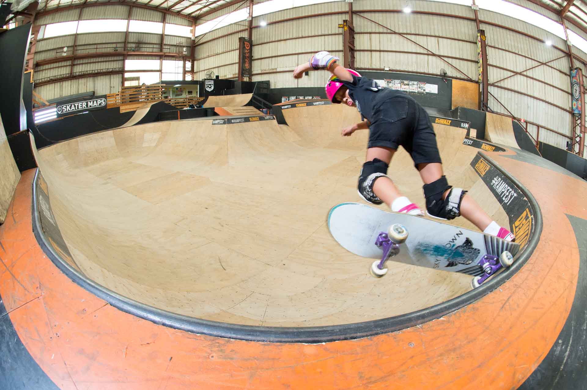Young female skateboarder learns coping trick at Rampfest indoor skatepark