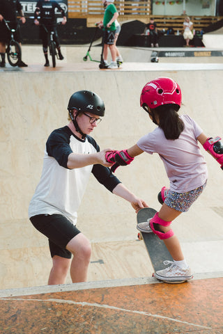 Alice learning to skateboard at RampFest with Coach Bailey