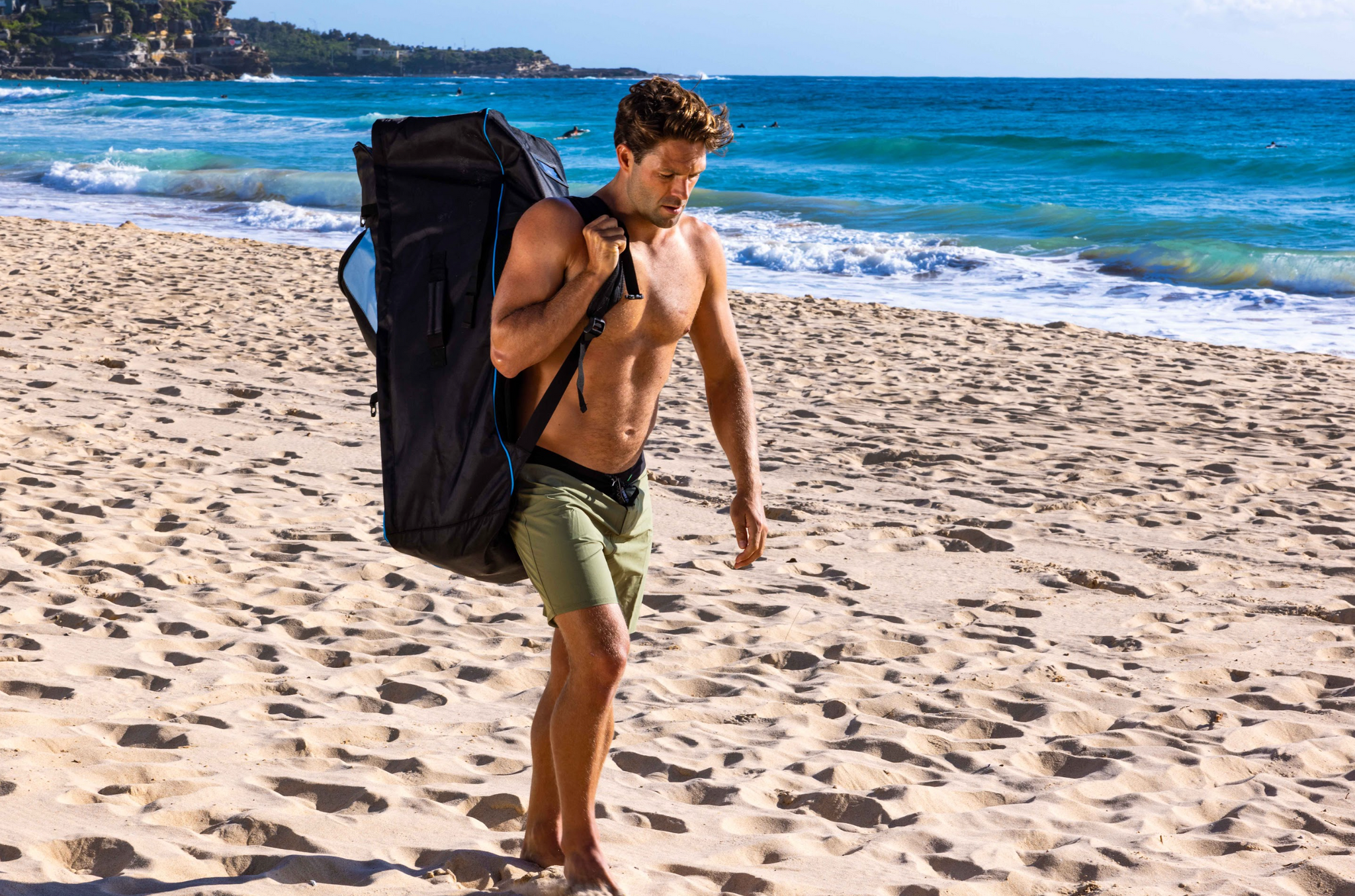 Man with Inflatable Stand Up Paddle Board in backpack on beach