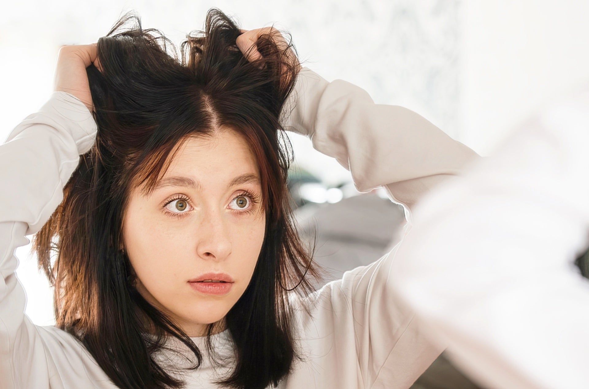 Woman with tousled hair looking surprised, showcasing the effects of hair styling products.