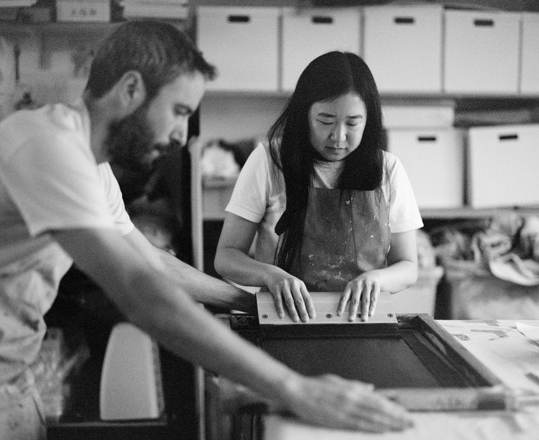 A black and white photo of Lucy and Patrick screen printing