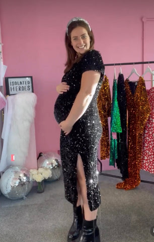 Woman wearing isolated heroes black sequin plus size dress as a pregnancy outfit for a wedding or party. available in sizes 12-28