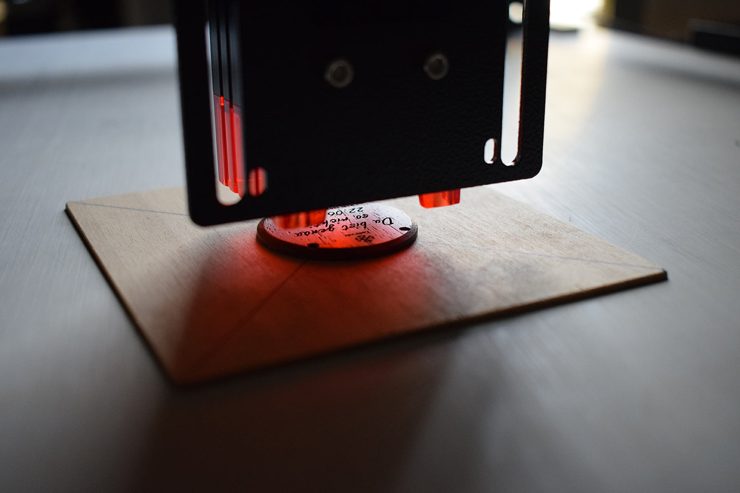 Procédé de gravure laser d'une horloge Zeitholz personnalisée à lumière rouge sur un socle en bois naturel, vue détaillée.