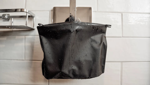 FlatPak™ Zipper Toiletry Case repelling water and hanging in a bathroom
