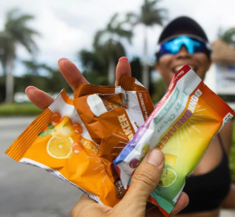 Happy female runner in blue sunglasses reaching for sports nutrition supplements outdoors