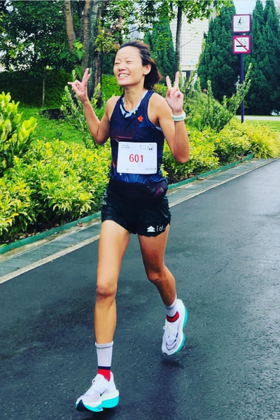 Woman running in a marathon waving at the camera and smiling