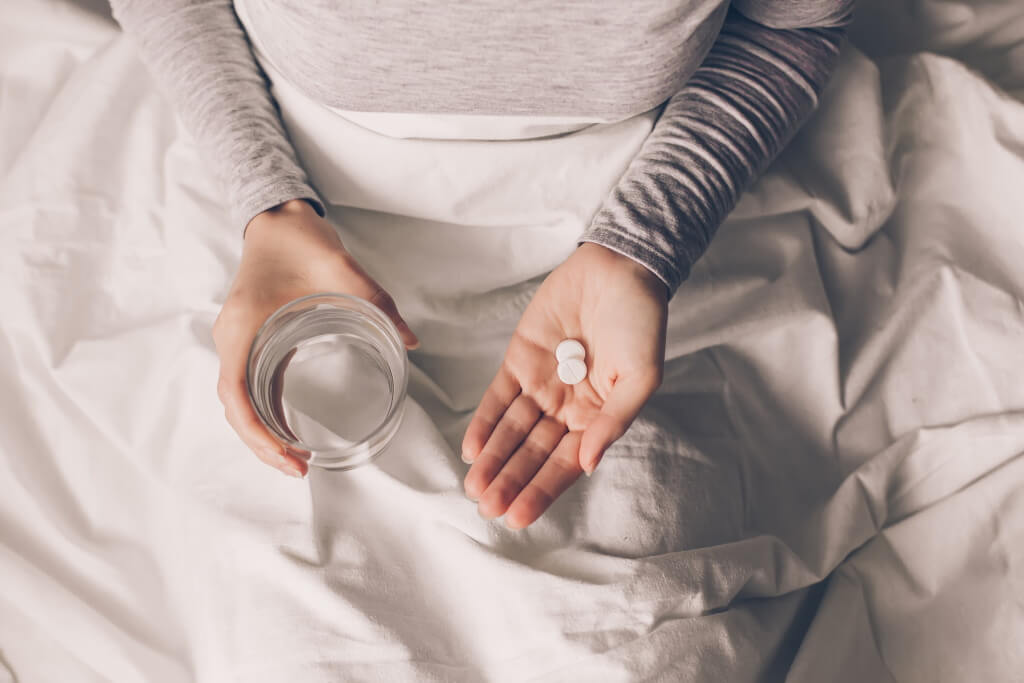 Zinco e sistema immunitario: donna a letto con integratori di zinco