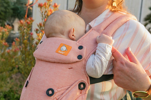 A closeup of a newborn sleeping ina Tula Carrier.