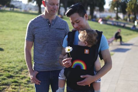 A family of two fathers and their son walking in a park.